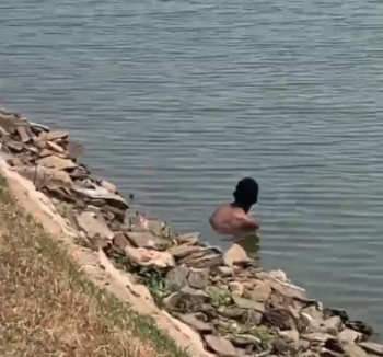 Homem se refresca de calor de 40 C na lagoa de parque em Cuiab