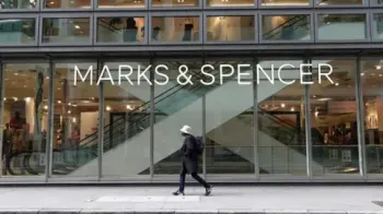 Um homem passa pela frente de vidro de uma loja Marks and Spencer no centro de Londres