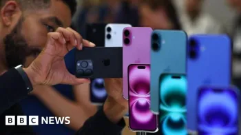 Homem olhando para iphones em exibio em uma variedade de cores azul, verde e roxo