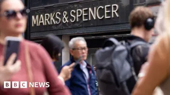 Pessoas andando em frente a uma loja Marks and Spencer.