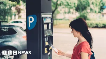 Getty Images Uma jovem de blusa vermelha, usando o celular ao lado de um parqu�metro