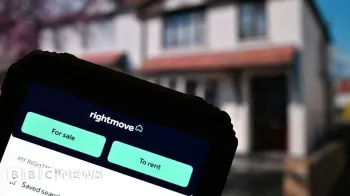 Getty Images O site Rightmove em uma tela de telefone exibida em frente a uma casa desfocada no fundo