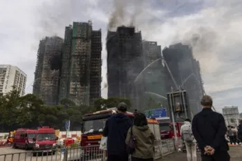 Pessoas observam pr�dios residenciais atingidos por inc�ndio em Hong Kong� Isaac Lawrence/Getty Images