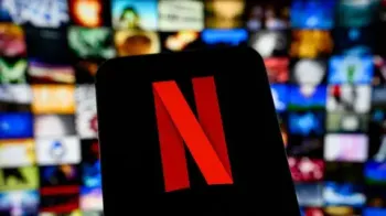 Getty Images: Logotipo da Netflix em uma tela de smartphone, com a plataforma e suas fileiras de filmes e s�ries desfocadas ao fundo.
