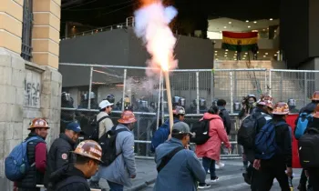 Um manifestante segura um sinalizador enquanto mineiros marcham em frente � pol�cia de choque durante um protesto organizado pelo Centro Oper�rio Boliviano (COB), que pede a ren�ncia do presidente Rodrigo Paz, em La Paz