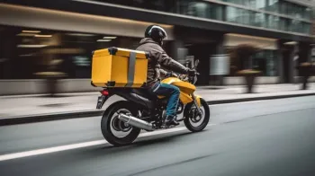 Entregador de aplicativo usando moto como ferramenta de trabalho.