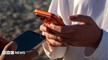 Dois jovens segurando smartphones pr�ximos um do outro, trocando detalhes. Cr�dito: Getty Images