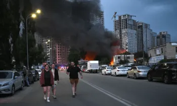 Moradores passam por garagens em chamas ap�s um ataque com m�sseis russos em Kiev (GENYA SAVILOV / AFP)