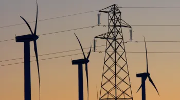 Silhuetas de turbinas e�licas e postes de eletricidade ao p�r do sol