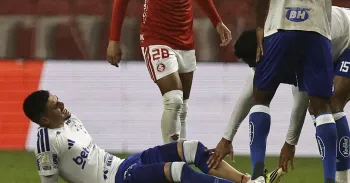 Ap�s ser atingido, o atleta cruzeirense ficou ca�do no gramado, com sangramento na perna esquerda - Foto: Roberto Vin�cius/AGIF