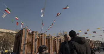 Homens iranianos conversam sob bandeiras do pa�s, do lado de fora do Grande Bazar, em Teer�. Morteza Nikoubazl/NurPhoto via Getty Images
