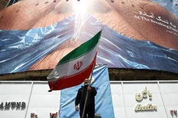 Homem segura bandeira iraniana perto de outdoor anti-EUA em Teer�; Majid Asgaripour/WANA via REUTERS