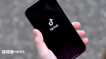 Uma jovem segurando seu iPhone mostrando o aplicativo TikTok.