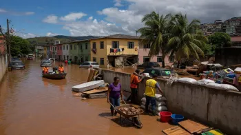 Equipes de resgate e m�quinas pesadas trabalhando na reconstru��o de rodovias ap�s fortes inunda��es em �reas urbanas brasileiras no ano de 2026.
