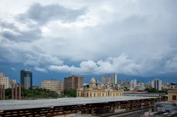Foto a�rea mostrando nuvens escuras e chuva intensa sobre �rea urbana com tr�fego de ve�culos sob alerta clim�tico. (Pexels)